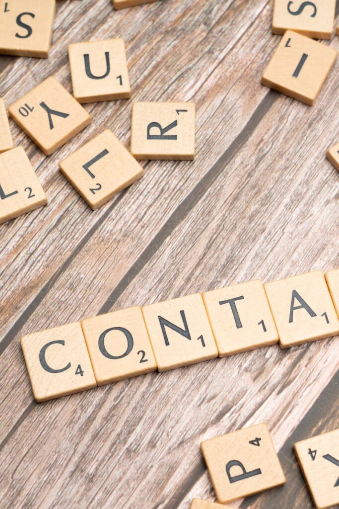 Contact Scrabble-style letter tiles spelling 'contact' on wooden surface.